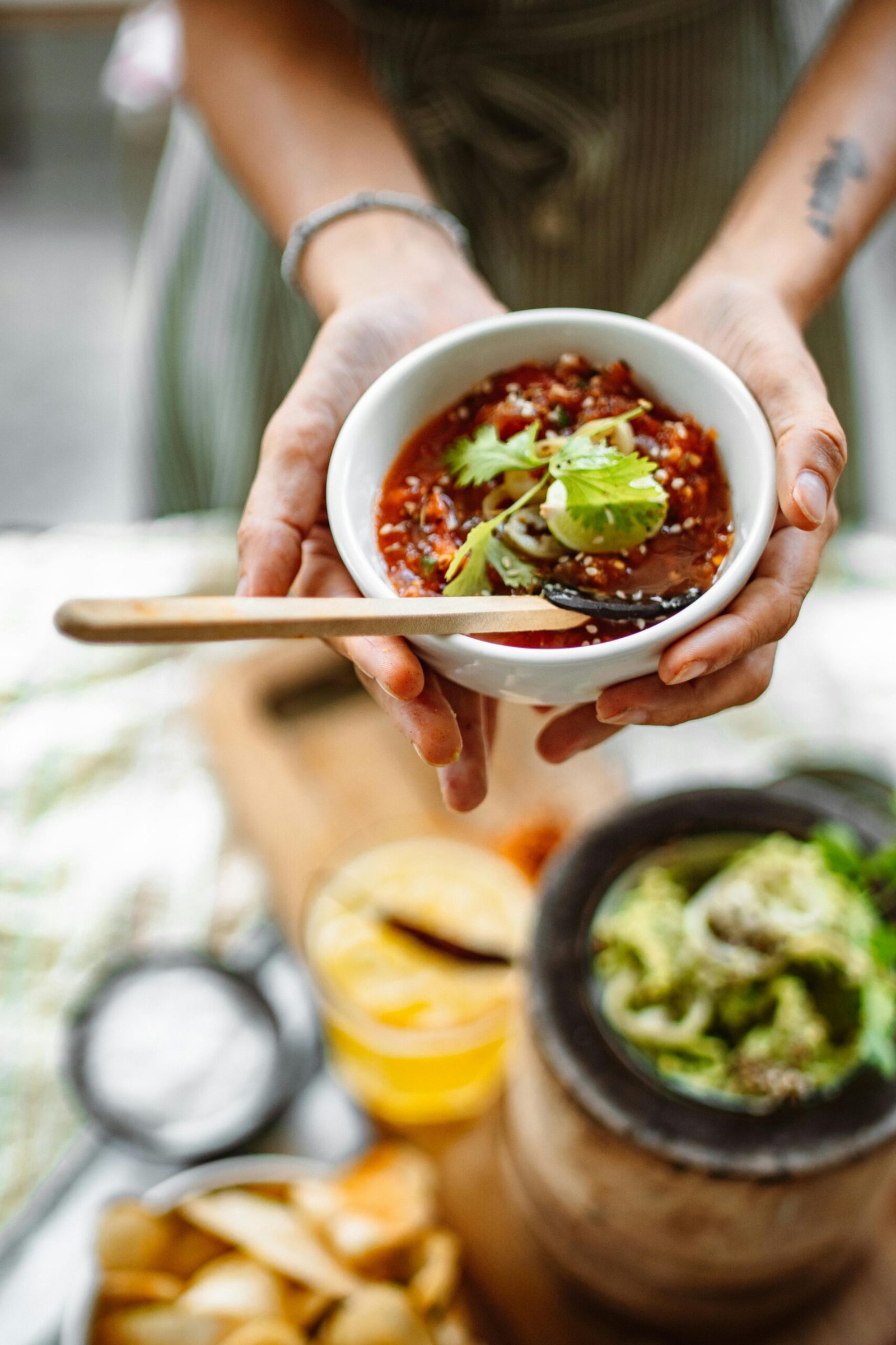 Close-up of a person holding a bowl of spicy salsa garnished with cilantro.